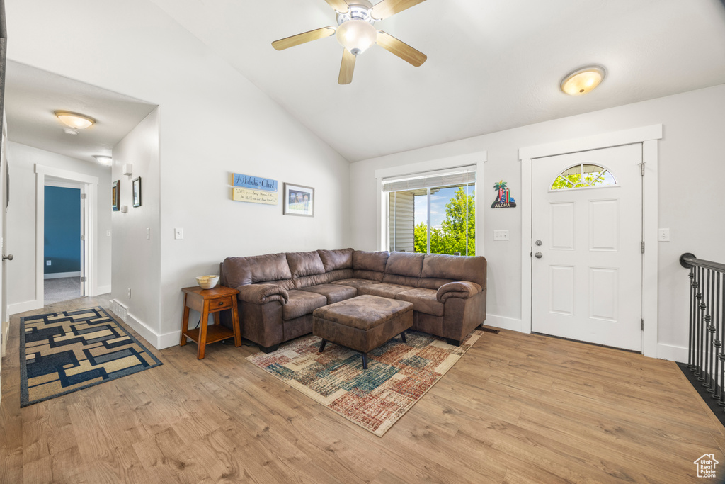 Living room with wood finished floors, ceiling fan, vaulted ceiling, and baseboards