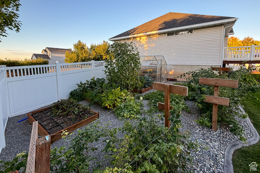 View of yard featuring a garden, a greenhouse, fence, and an outdoor structure