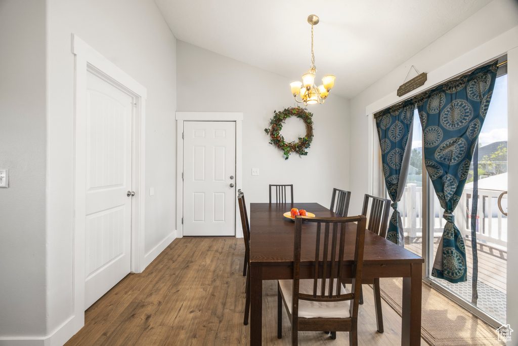 Dining space featuring a chandelier, vaulted ceiling, wood finished floors, and baseboards