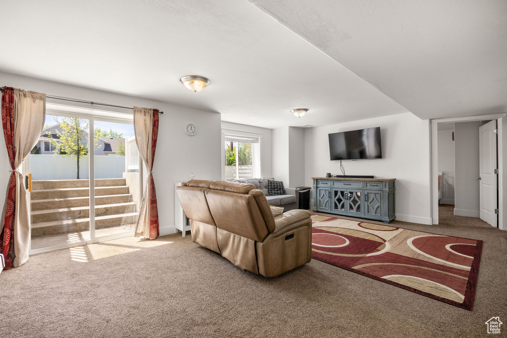 Living room with carpet, baseboards, and stairway