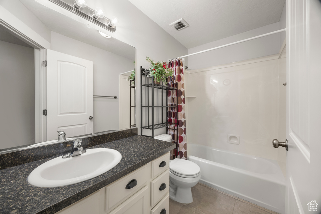 Full bathroom with tile patterned flooring, toilet, vanity, and shower / bath combo