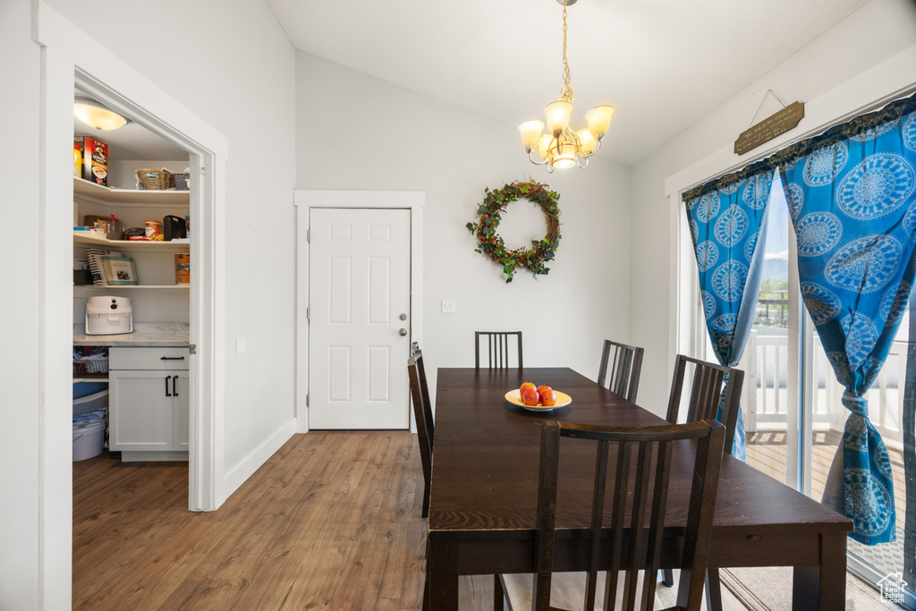 Dining room featuring lofted ceiling, a chandelier, wood finished floors, and baseboards