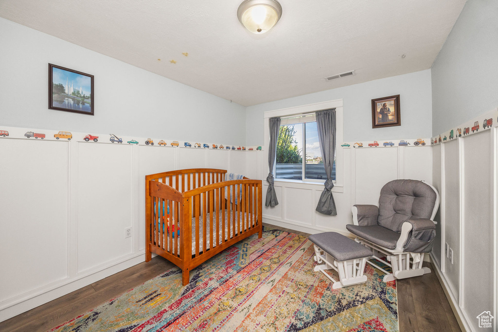 Bedroom with wood finished floors and a decorative wall