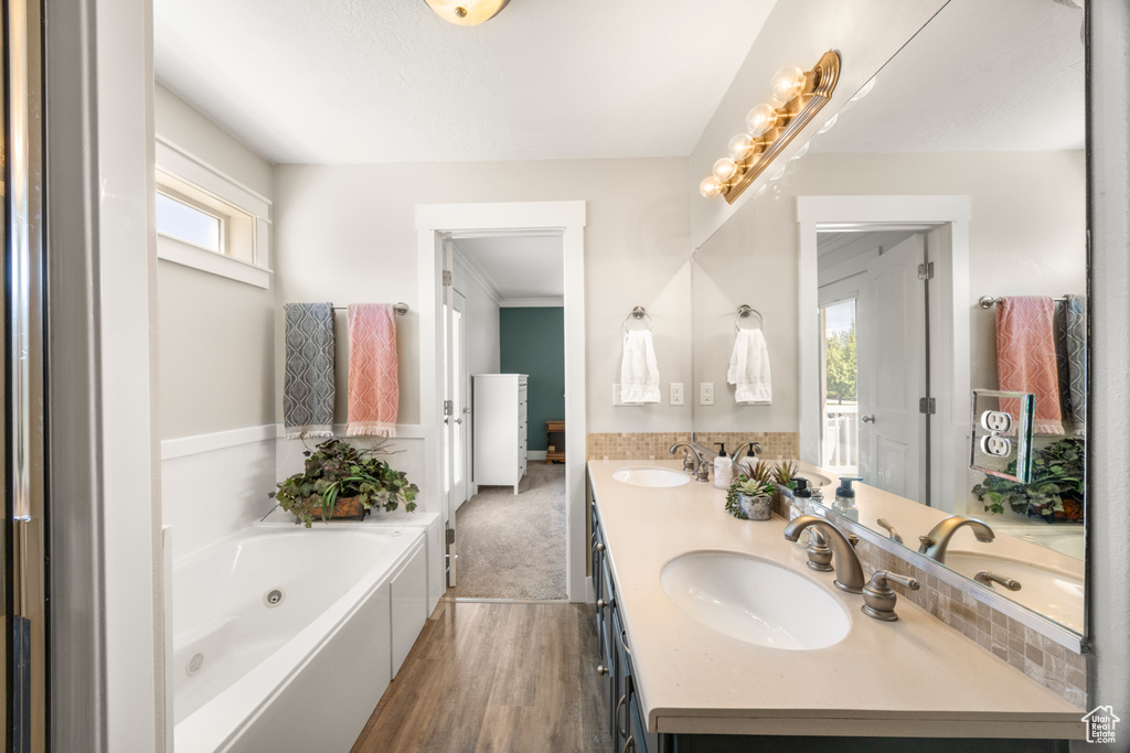 Bathroom featuring a whirlpool tub, wood finished floors, and double vanity