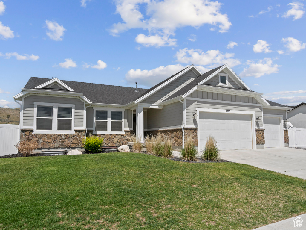 View of front facade featuring stone siding, board and batten siding, driveway, and a garage