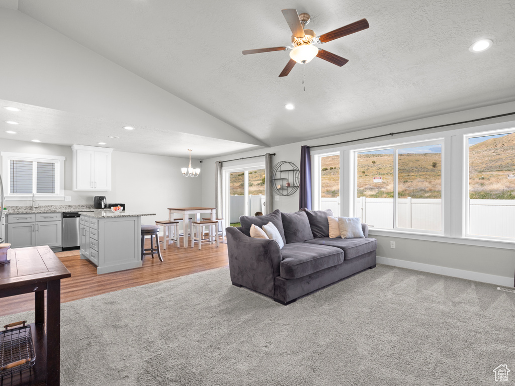 Living room with vaulted ceiling, recessed lighting, ceiling fan, a chandelier, and baseboards