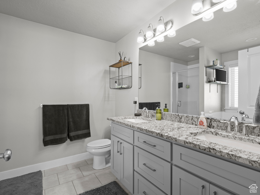 Full bath featuring a shower stall, tile patterned flooring, toilet, double vanity, and baseboards