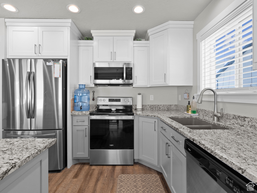 Kitchen featuring appliances with stainless steel finishes, a sink, recessed lighting, wood finished floors, and white cabinetry