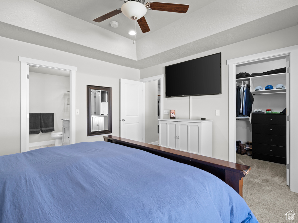 Carpeted bedroom with a spacious closet, connected bathroom, a closet, and ceiling fan