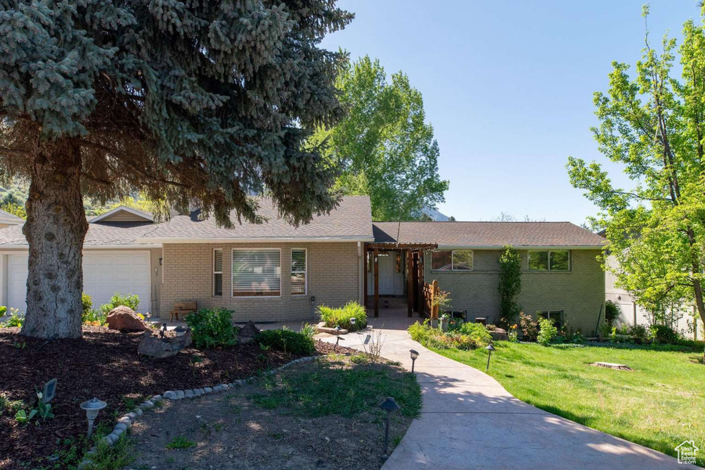 Ranch-style house with brick siding, an attached garage, and a front yard