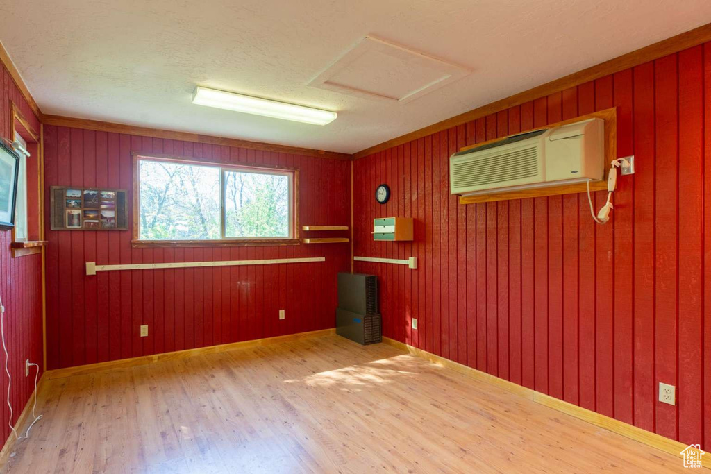 Spare room featuring wood finished floors, an AC wall unit, attic access, and wood walls