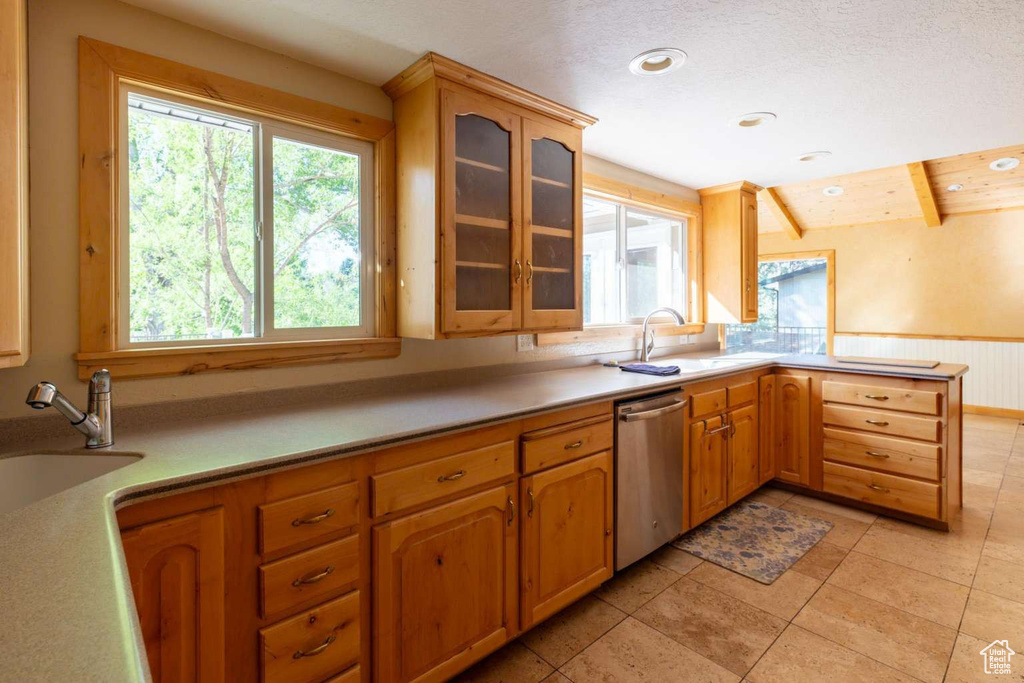 Kitchen with dishwasher, a sink, glass insert cabinets, light countertops, and wainscoting