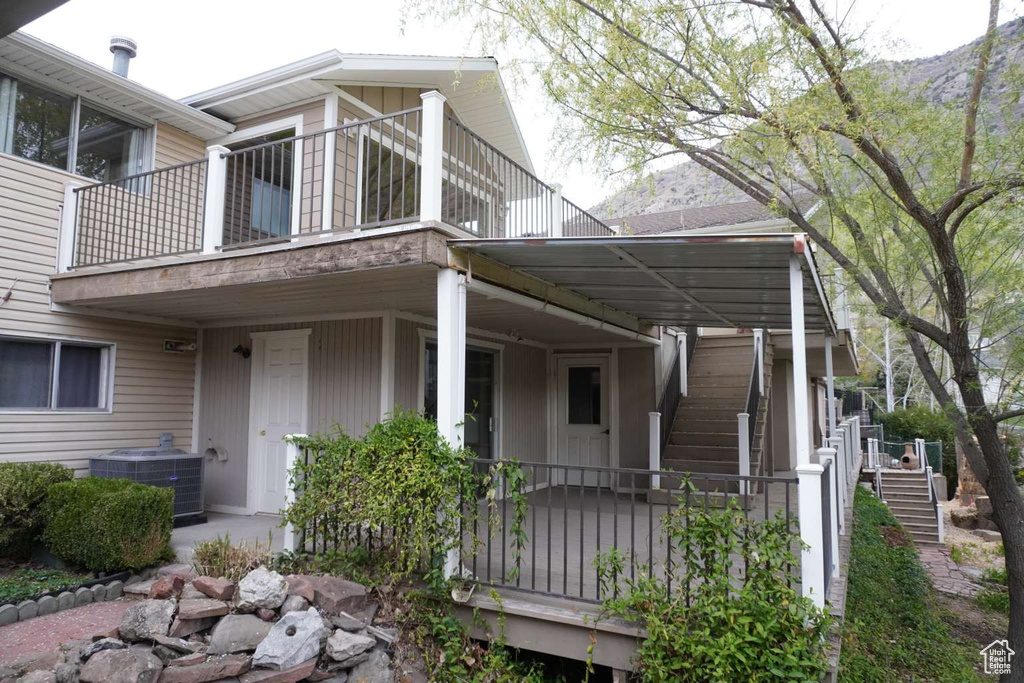 View of side of home with stairs, central AC unit, a balcony, and a mountain view