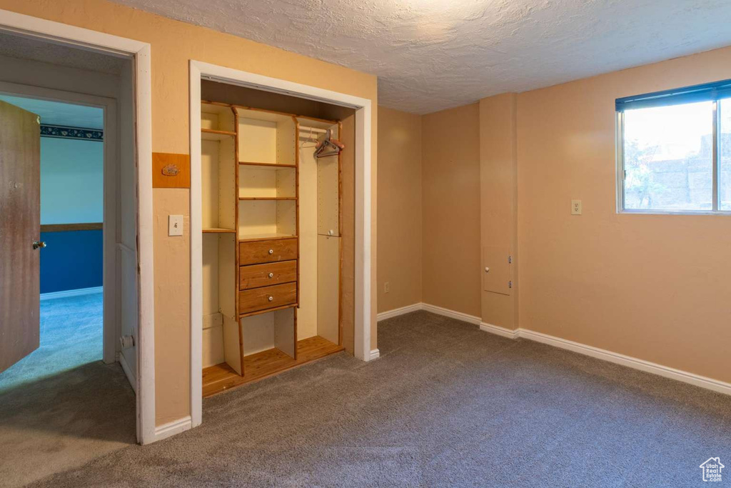 Unfurnished bedroom with carpet, a textured ceiling, and baseboards