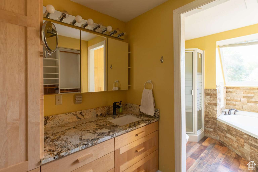 Bathroom with a shower stall, wood finished floors, vanity, and a bath