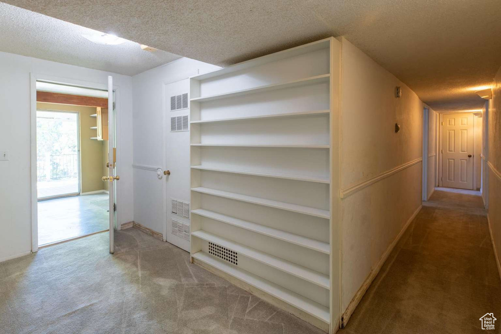 Hall featuring a textured ceiling, carpet flooring, and baseboards