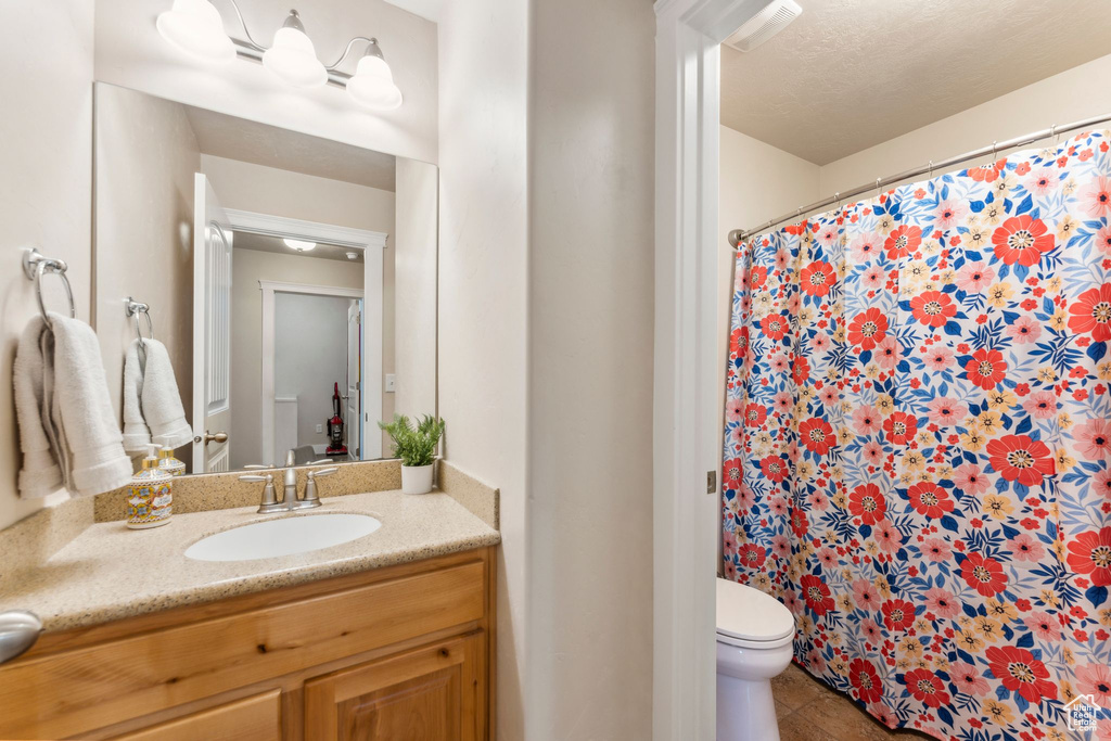 Full bathroom featuring toilet, vanity, a shower with curtain, and tile patterned floors