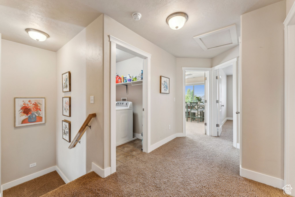 Hall with attic access, carpet, washer / dryer, an upstairs landing, and baseboards