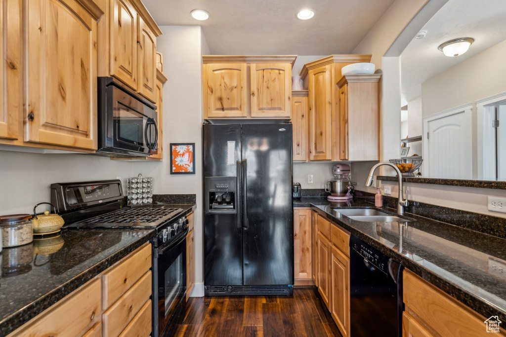 Kitchen with black appliances, a sink, dark wood-style flooring, dark stone counters, and recessed lighting