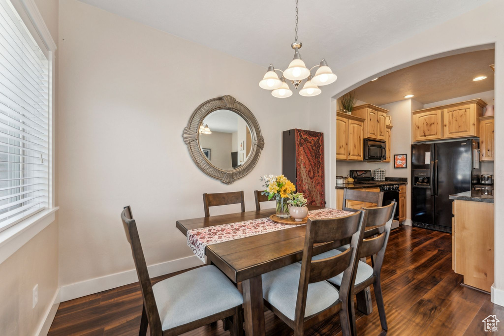 Dining area with arched walkways, a chandelier, dark wood-type flooring, recessed lighting, and baseboards