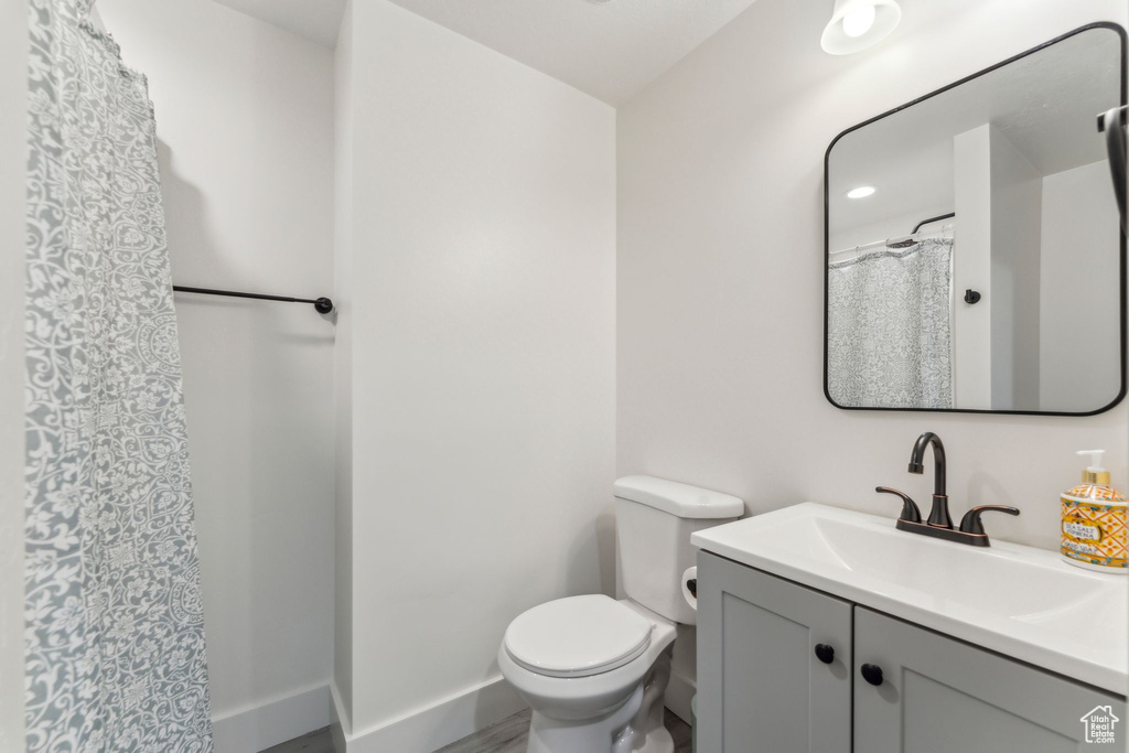 Bathroom featuring toilet, baseboards, vanity, and curtained shower