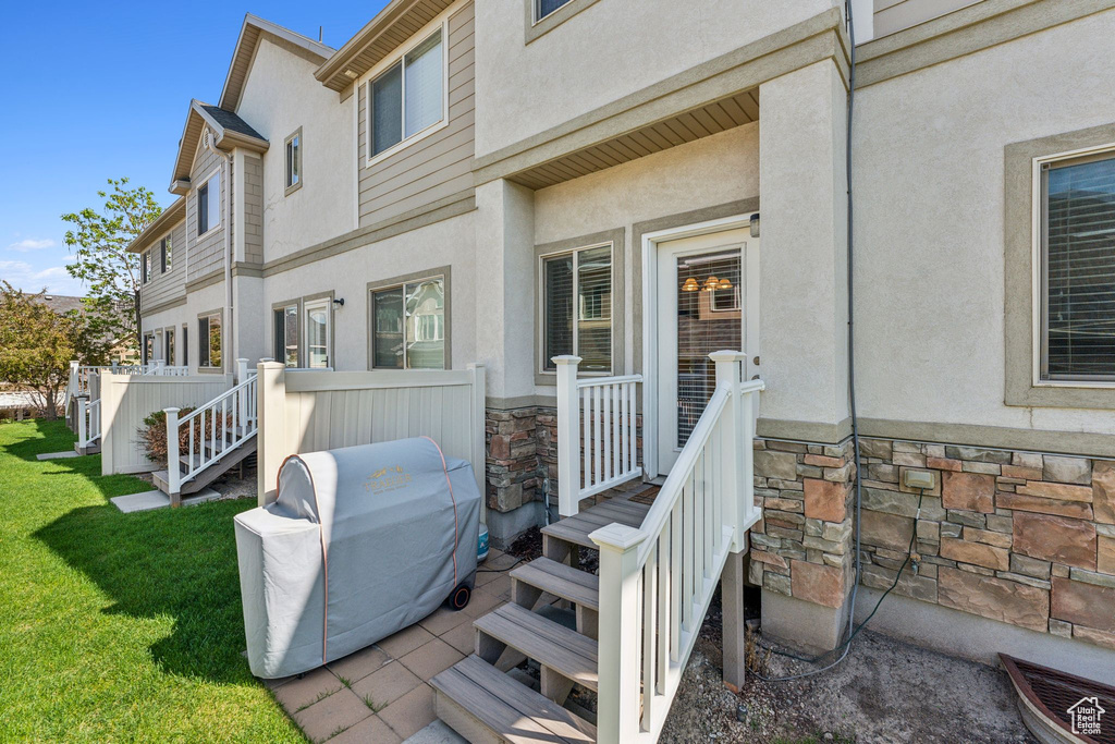 Back of house with stone siding, stucco siding, and a yard