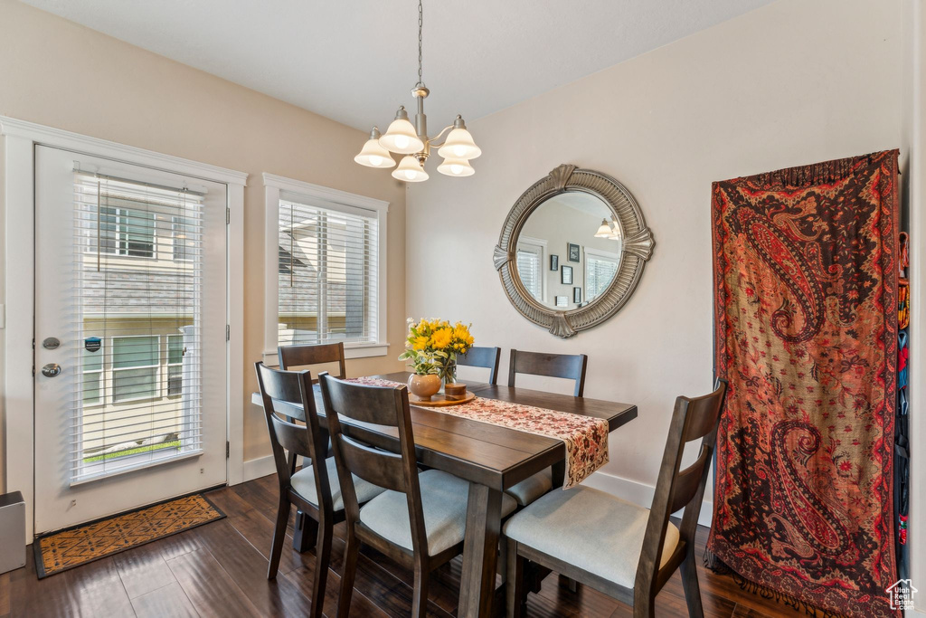 Dining area featuring a chandelier, dark wood-style flooring, and baseboards