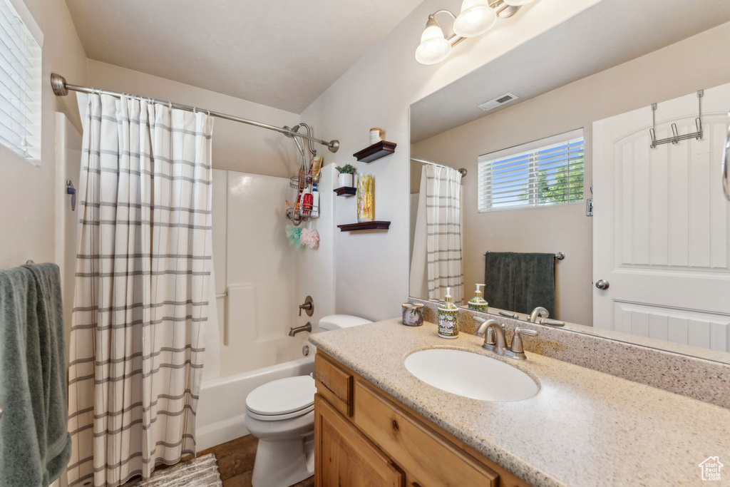 Full bathroom with toilet, shower / bath combination with curtain, and vanity