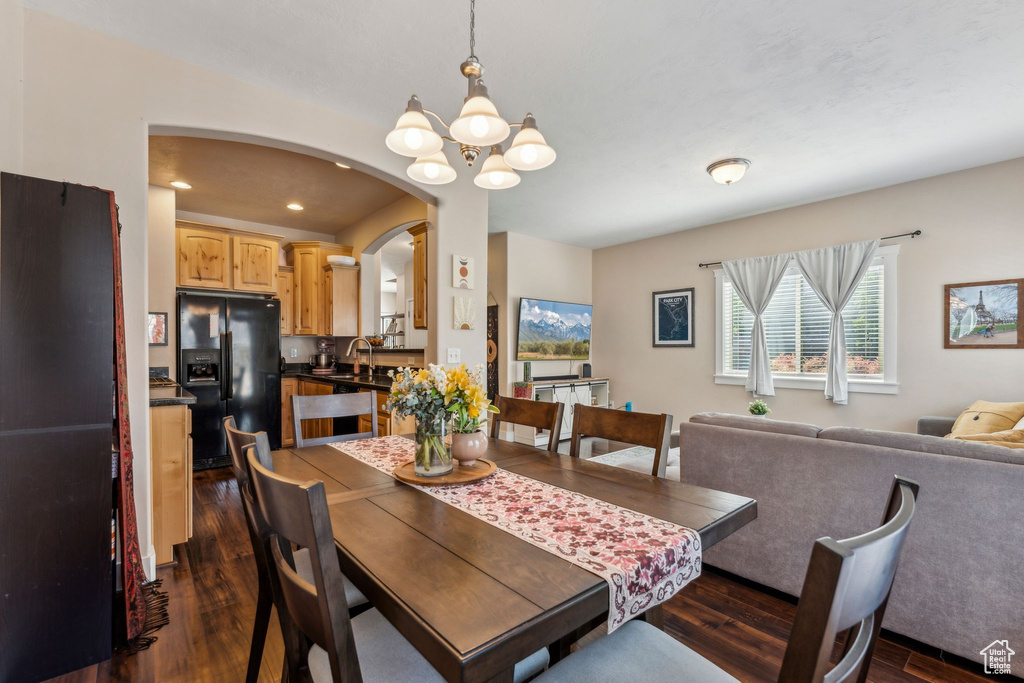 Dining area featuring dark wood-style floors, a chandelier, arched walkways, and recessed lighting