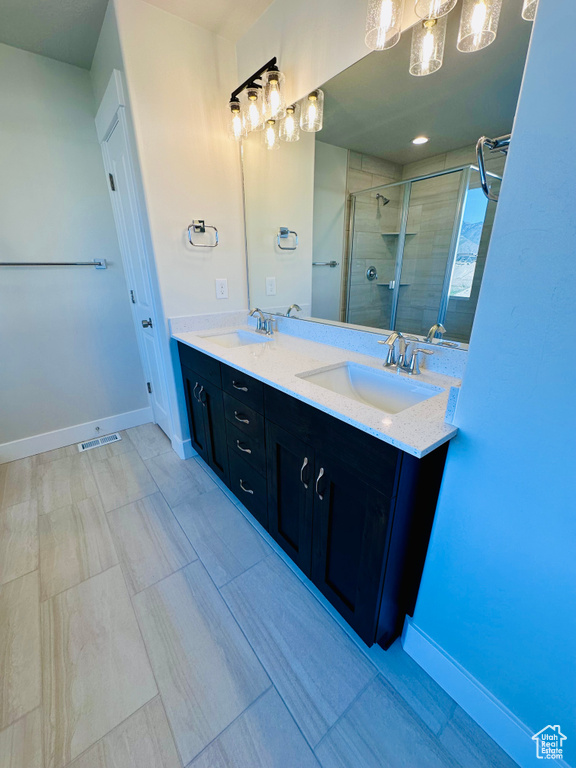 Full bath with a shower stall, double vanity, and baseboards