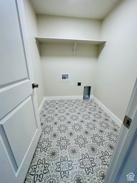 Clothes washing area with hookup for a washing machine, baseboards, and tile patterned floors