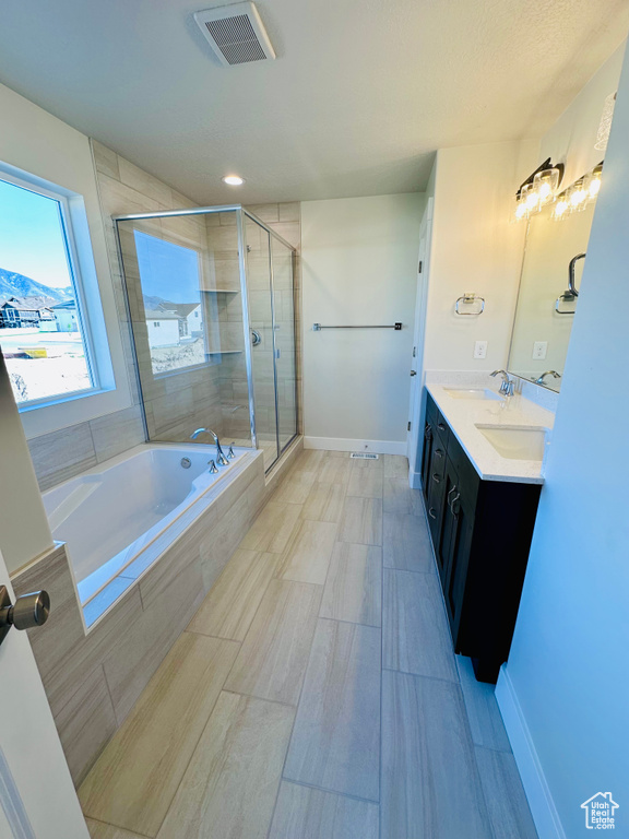 Bathroom with a bath, a stall shower, double vanity, and baseboards