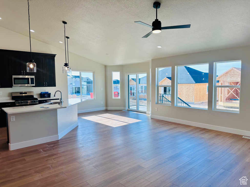 Kitchen featuring appliances with stainless steel finishes, dark cabinetry, a textured ceiling, ceiling fan, and lofted ceiling