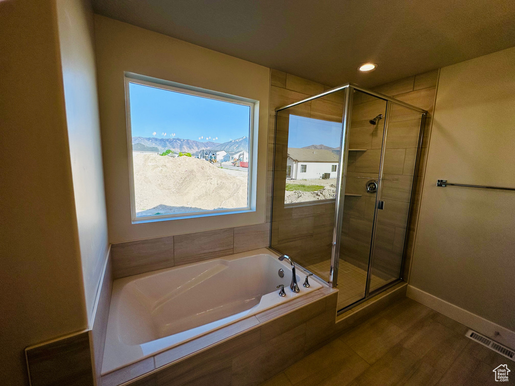 Bathroom with a stall shower, a garden tub, baseboards, and recessed lighting