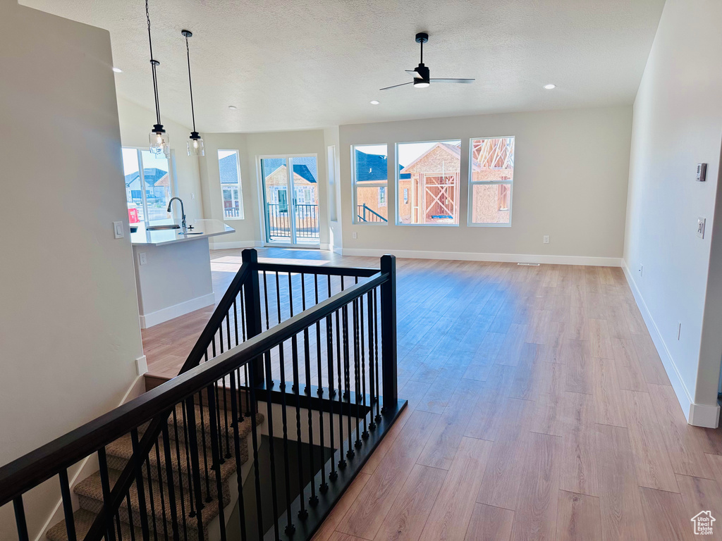 Hall featuring an upstairs landing, baseboards, light wood finished floors, and recessed lighting