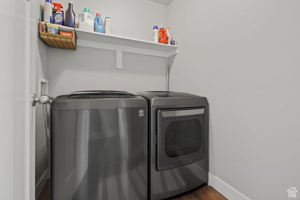 Clothes washing area with separate washer and dryer, baseboards, and dark wood-style flooring