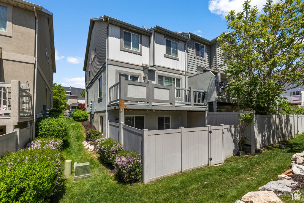 Rear view of property with fence, stucco siding, and a balcony
