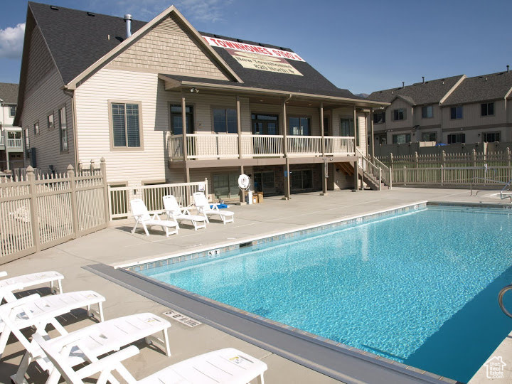 Community pool with a patio area, fence, and stairs