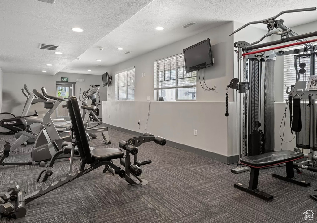 Exercise room featuring a textured ceiling, carpet flooring, baseboards, and recessed lighting