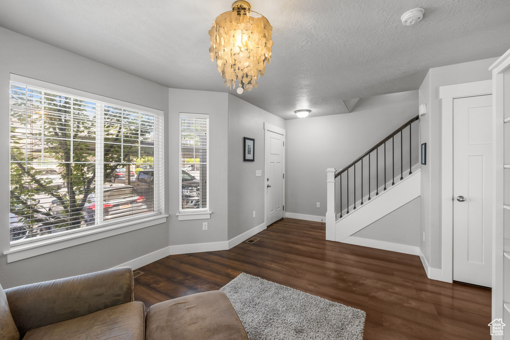 Entrance foyer featuring stairway, wood finished floors, baseboards, a chandelier, and a textured ceiling