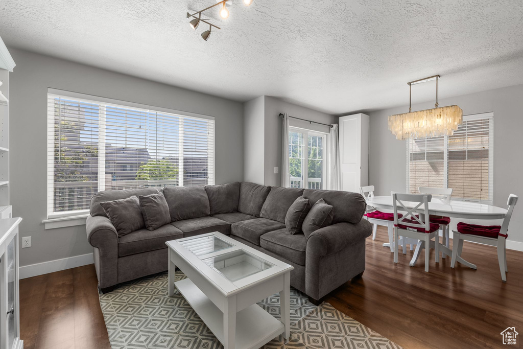 Living room with a textured ceiling, wood finished floors, a chandelier, and baseboards