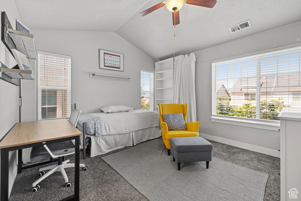 Carpeted bedroom featuring vaulted ceiling, multiple windows, baseboards, and ceiling fan