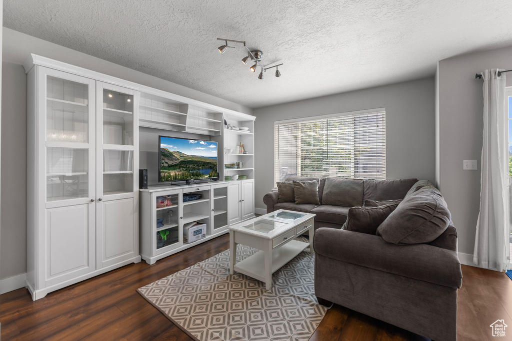 Living room featuring dark wood finished floors, a textured ceiling, and baseboards