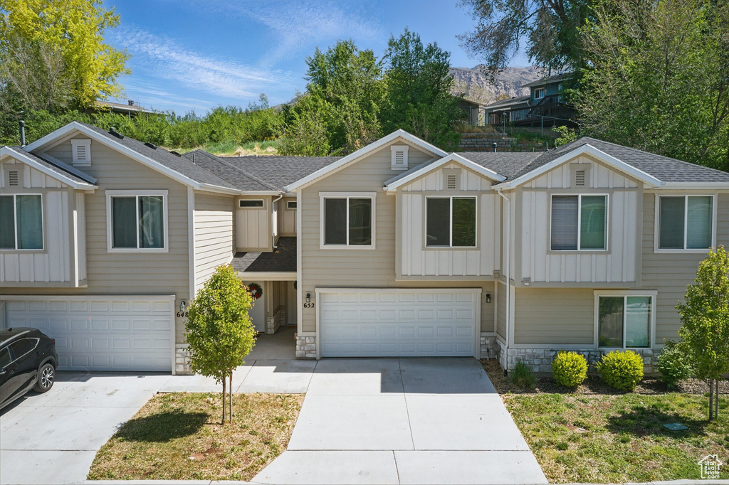 Townhome / multi-family property featuring board and batten siding, a garage, concrete driveway, and stone siding