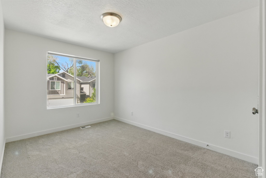 Empty room featuring baseboards, carpet floors, and a textured ceiling