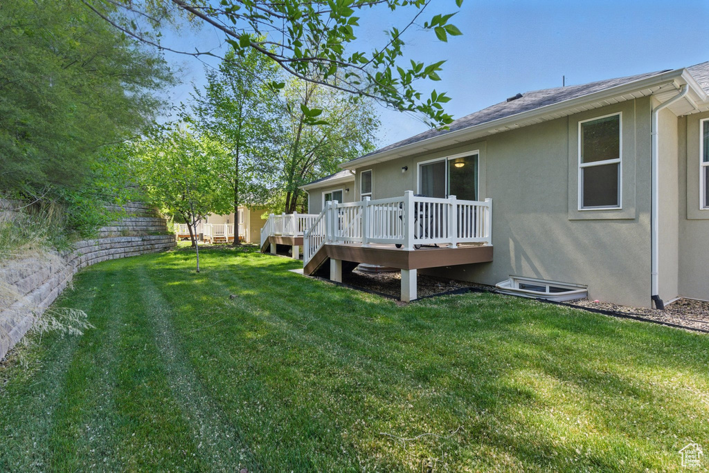 View of green lawn featuring a wooden deck