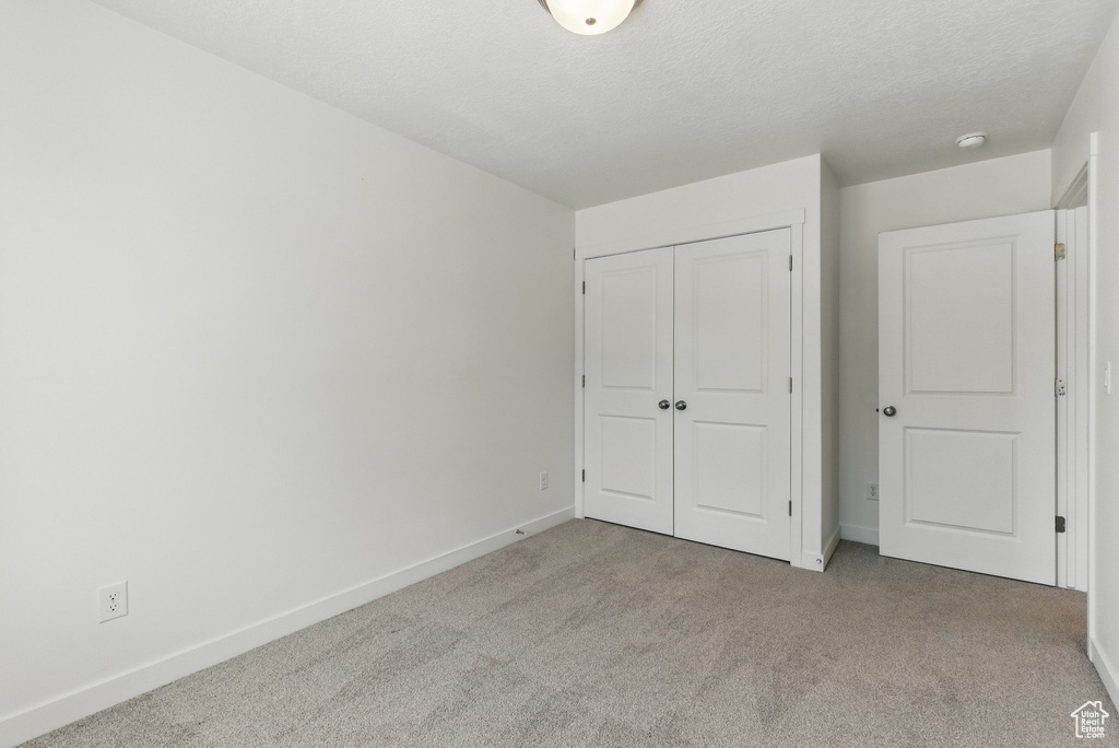 Unfurnished bedroom with carpet floors, baseboards, and a closet