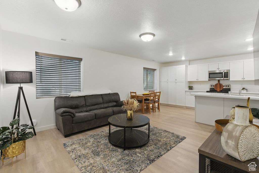 Living room featuring light wood finished floors, recessed lighting, and baseboards