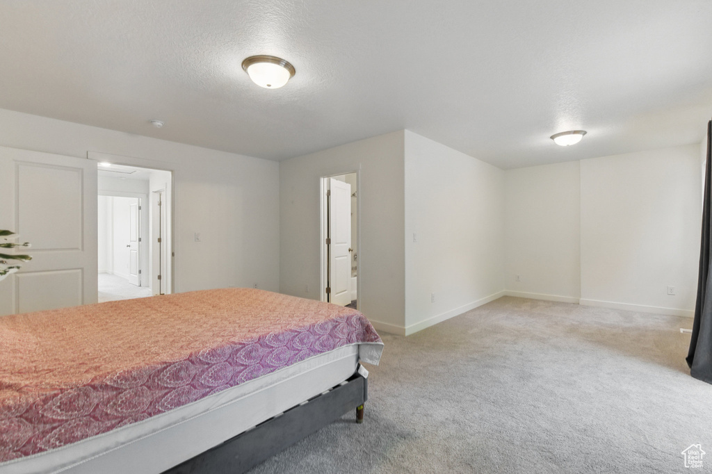 Bedroom with light carpet, baseboards, a textured ceiling, and attic access