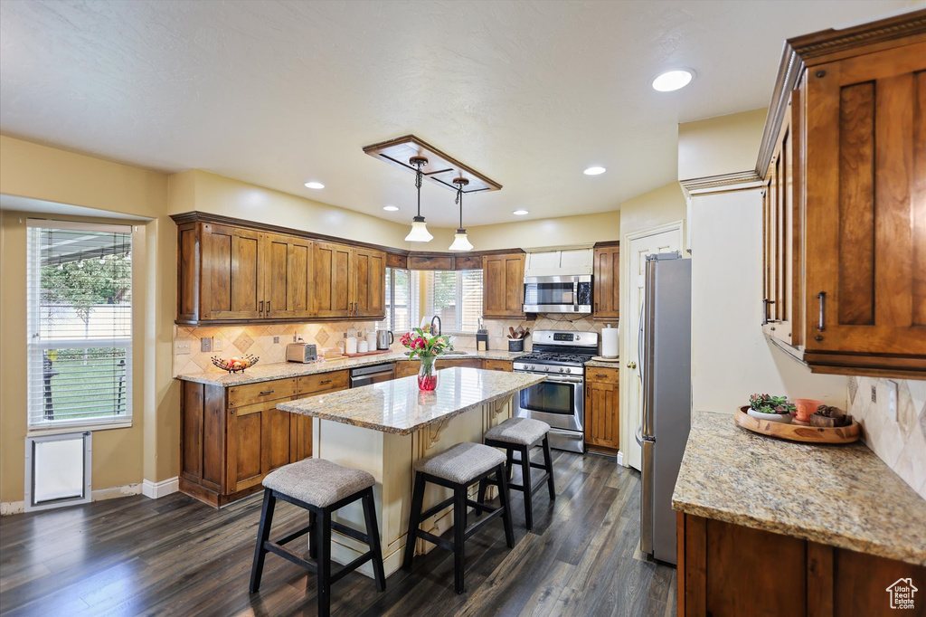 Kitchen with appliances with stainless steel finishes, a center island, dark wood finished floors, backsplash, and recessed lighting
